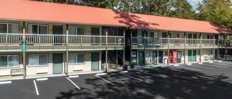 Un motel avec un toit rouge, une structure à deux étages et un parking.