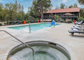 A pool area with lounge chairs and a hot tub.
