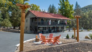 A two-story building with a red roof, outdoor seating area with orange chairs, and a flag. - Yosemite Westgate Lodge (Groveland)