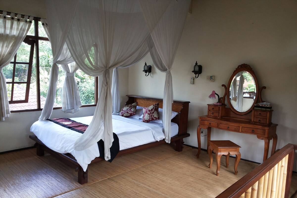 Une chambre à coucher avec un lit à baldaquin, une commode en bois et un miroir.