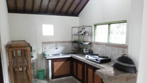Una cocina compacta con suelo de baldosas, un lavamanos empotrado, una estufa y una unidad de estanterías.