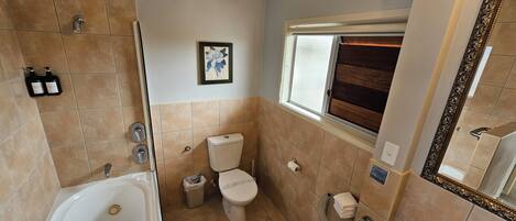 A bathroom with a bathtub, toilet, sink, and a window with a wooden blind.