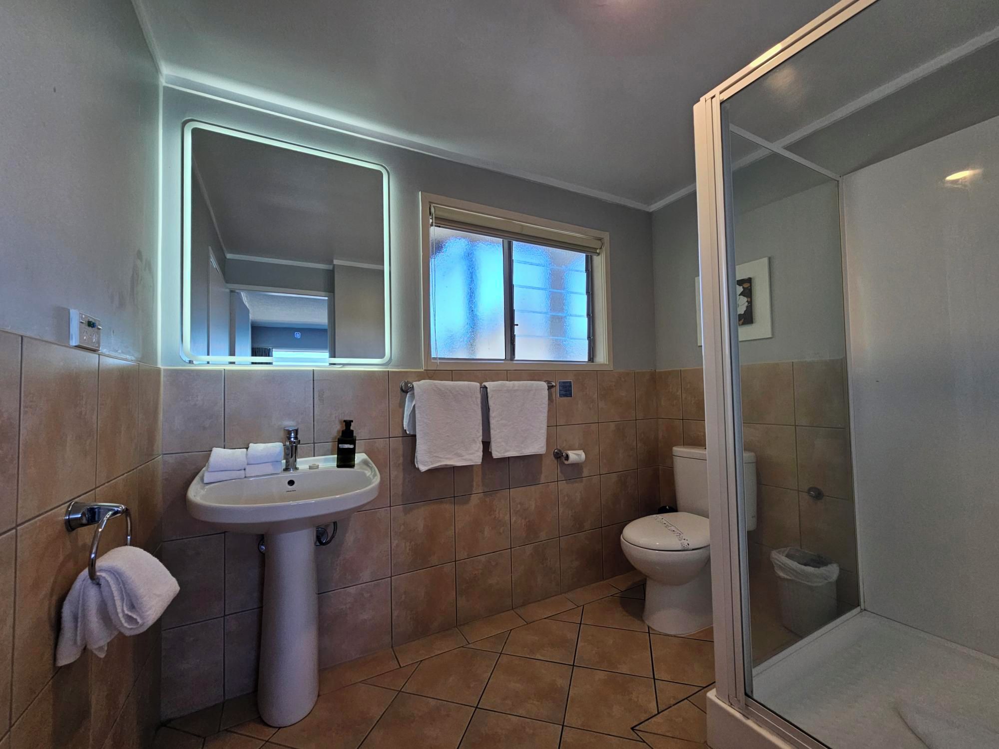 A modern bathroom with a sink, mirror, toilet, and shower.