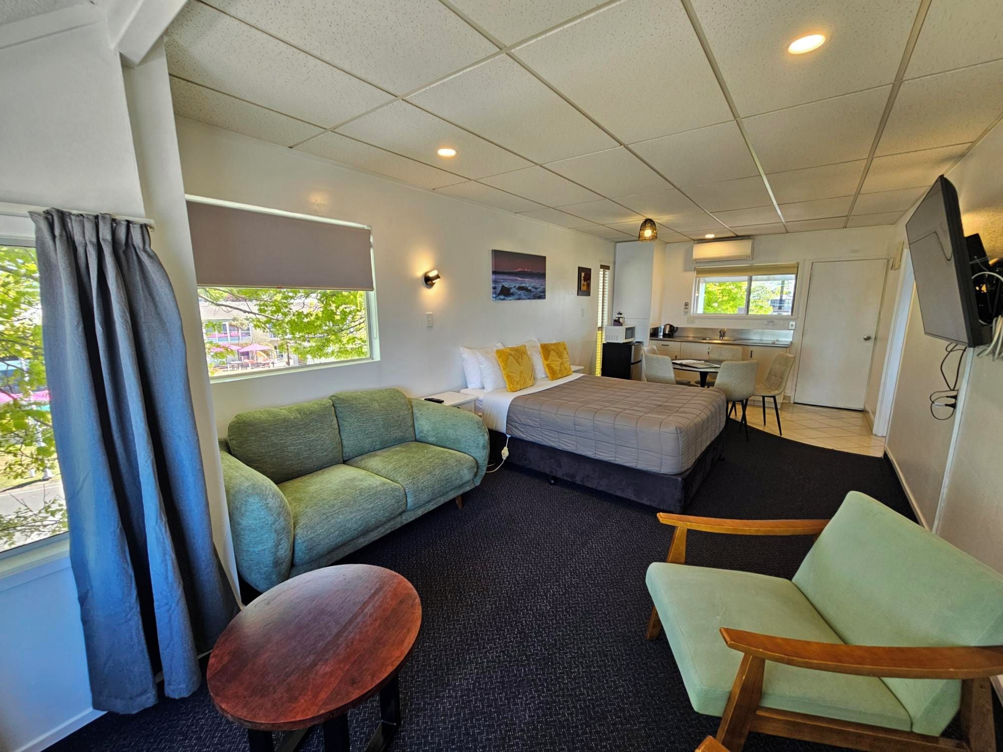 A compact hotel room with a sofa, a bed, a small table, and a chair.