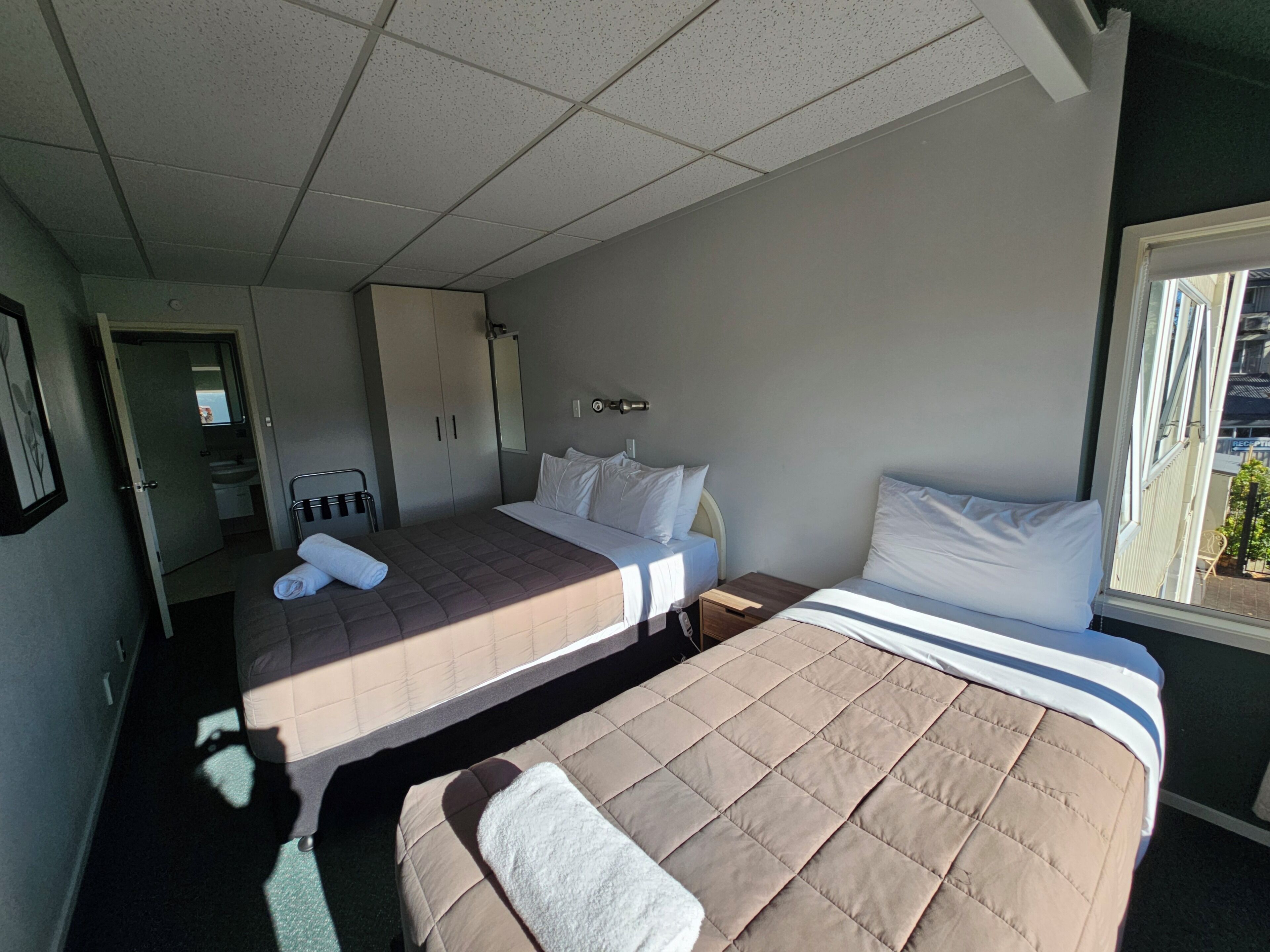 Une chambre d’hôtel avec deux lits, une salle de bain et une fenêtre donnant sur un beau paysage.
