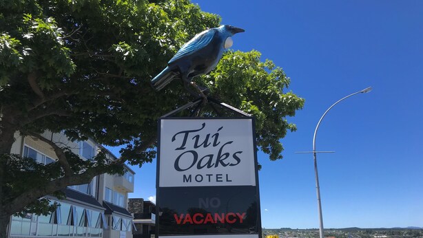 A sign for the Tini Oaks Motel advertising no vacancy, stunning views, and free WiFi.