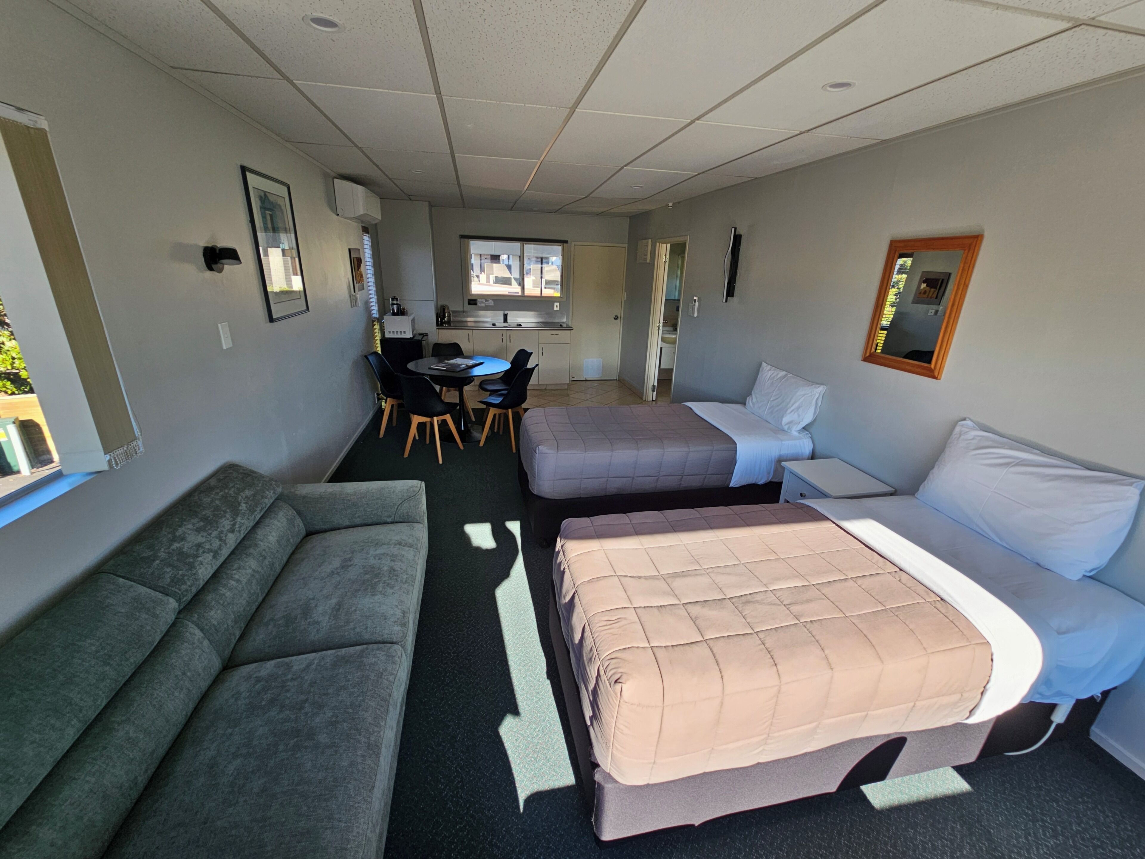 A room with a sofa, a bed, a small table, and a kitchenette.