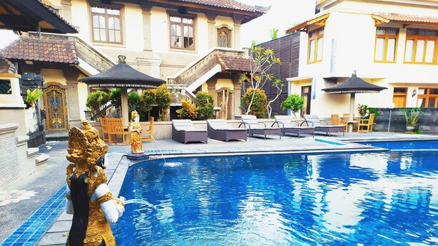 A swimming pool with a statue, lounge chairs, and a staircase leading to a building. - Pande Permai Bungalows (Ubud)
