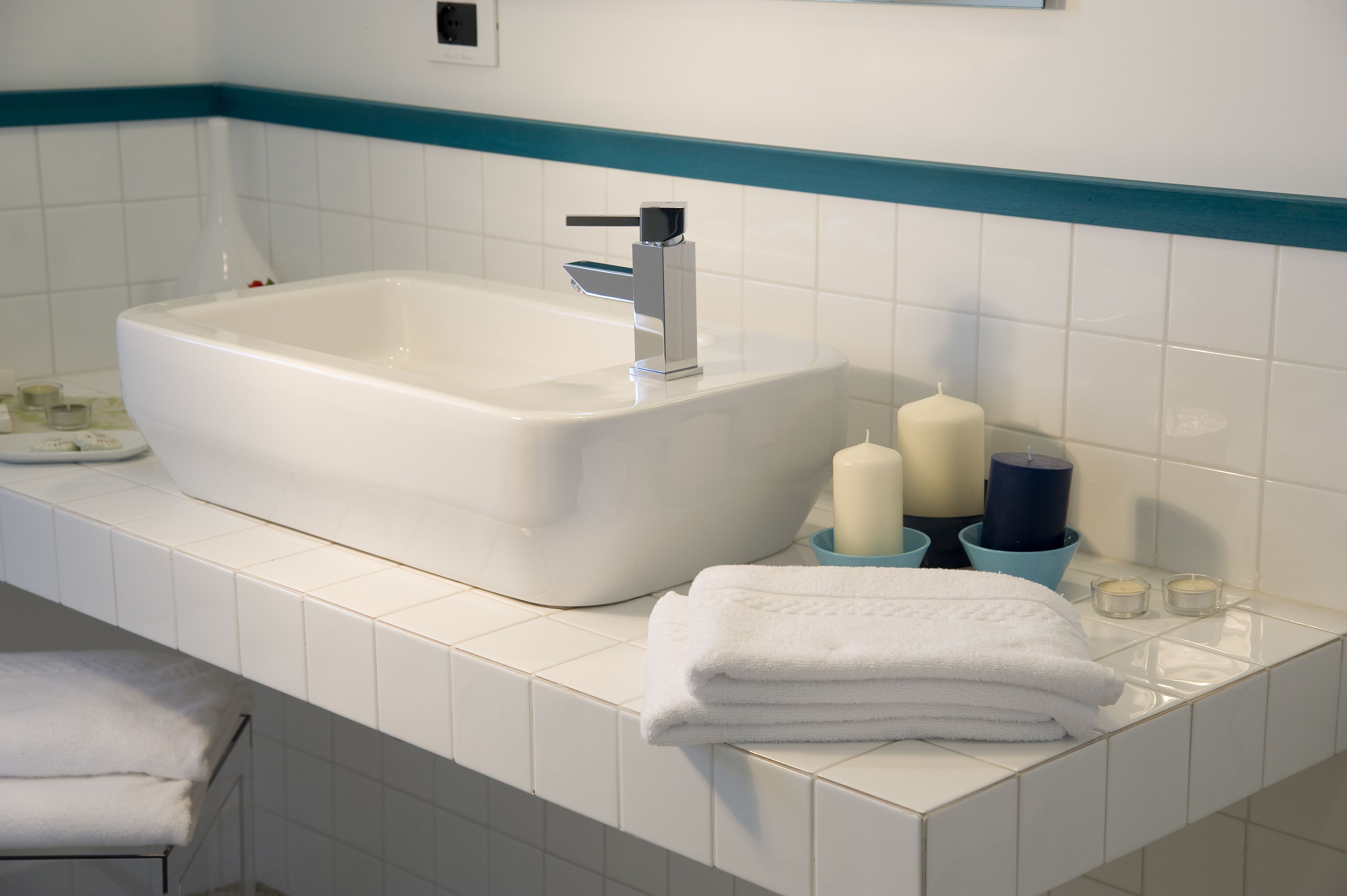 Une salle de bain avec une grande baignoire blanche, un robinet moderne et un mur recouvert de carreaux bleus et blancs.