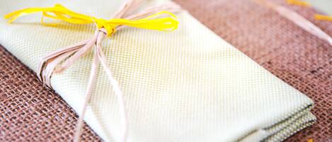 A neatly folded napkin tied with a yellow ribbon on a textured tablecloth.
