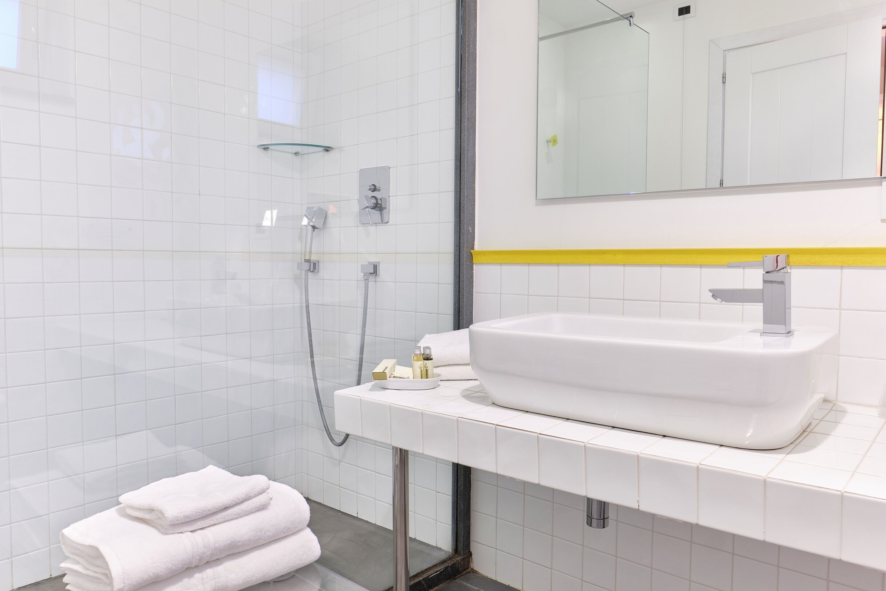 A modern bathroom with a white sink, mirror, and shower.