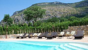 Un espace piscine avec des chaises longues et une vue sur les montagnes en arrière-plan.