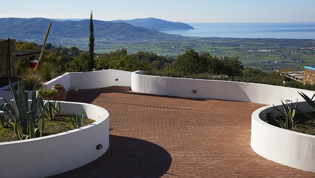Une terrasse sur le toit, dotée d’un sol en briques et de jardinières blanches remplies de plantes.