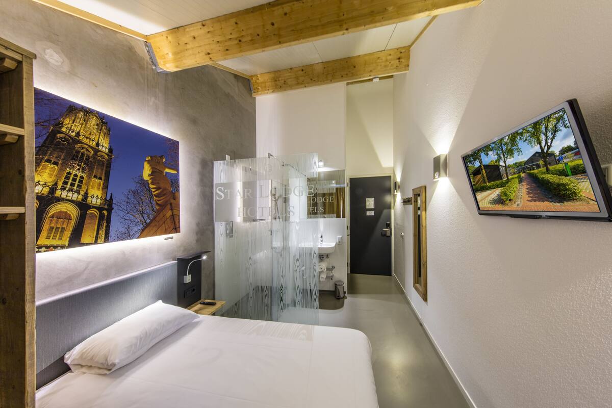 Ein Hotelzimmer mit Bett, Badezimmer und großem Fenster mit Blick auf die Stadt.