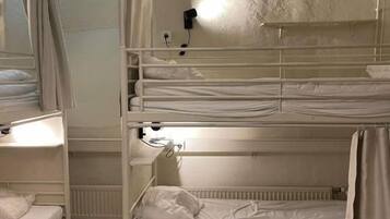 Habitación con literas, una ventana, una lámpara fijada a la pared y un radiador.