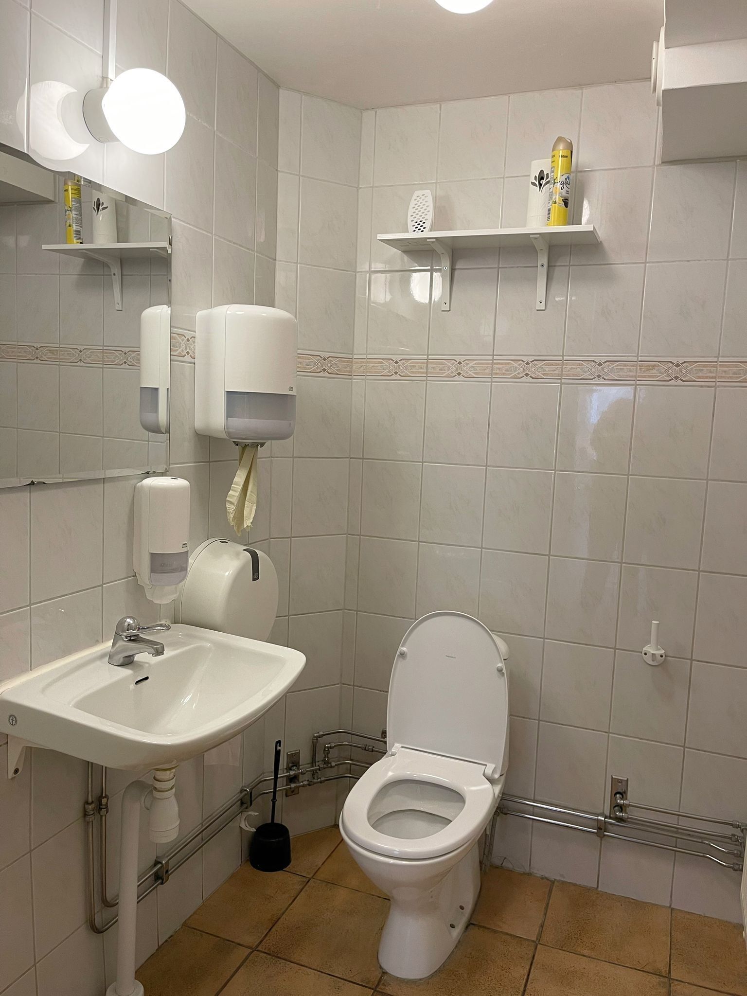 Baño con lavamanos, inodoro y secamanos.