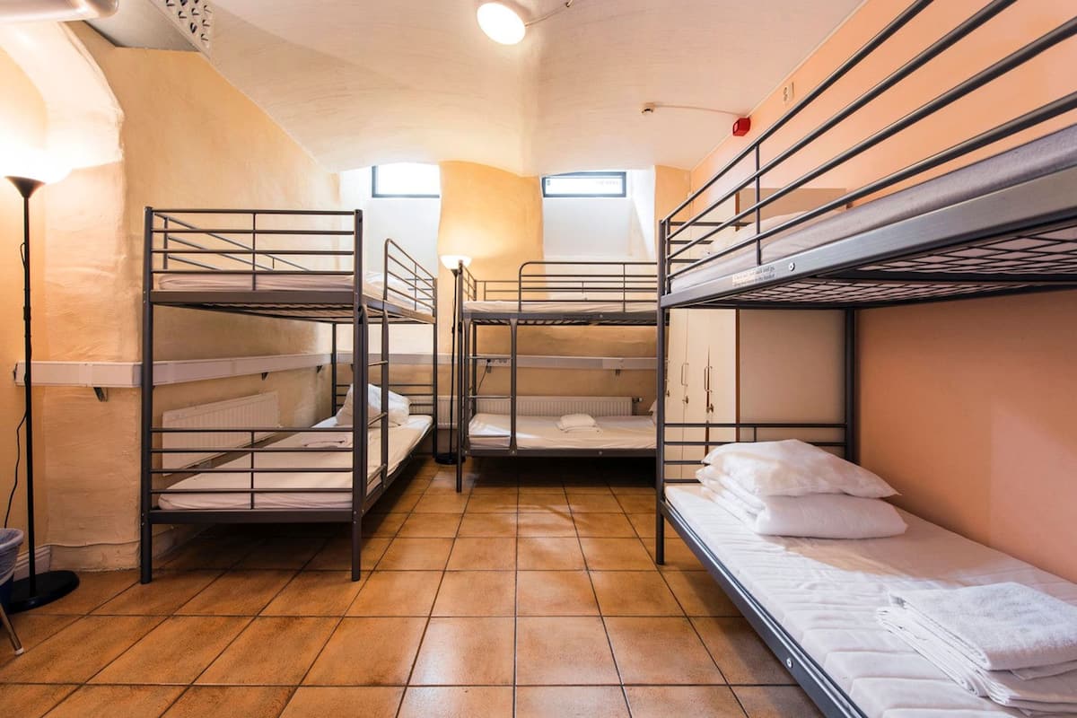 A dormitory room with bunk beds, a radiator, and a window.