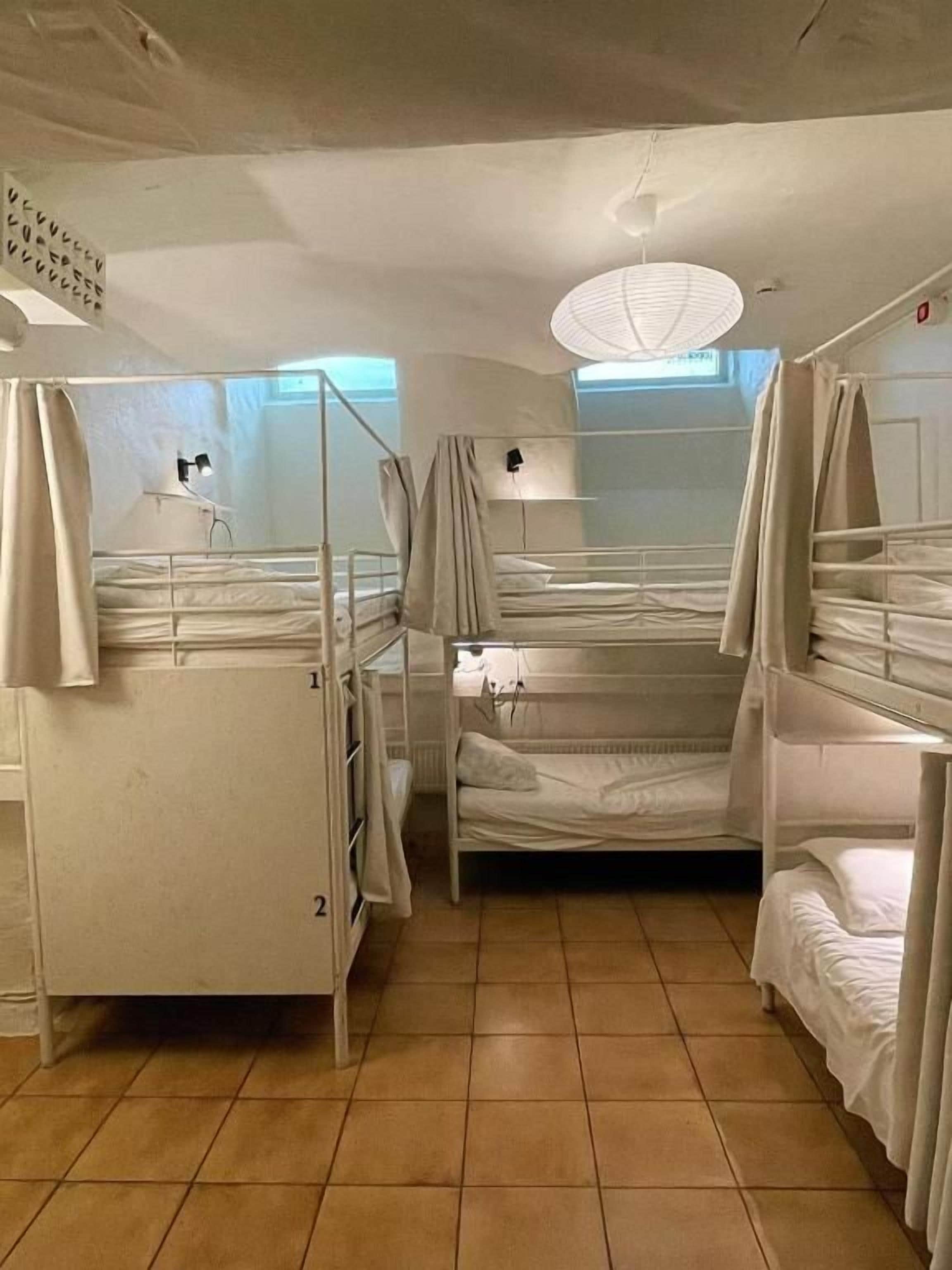 Un dormitorio con literas, ventilador de techo y ventana con cortinas.
