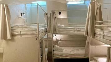 Un dormitorio con literas, ventilador de techo y ventana con cortinas.