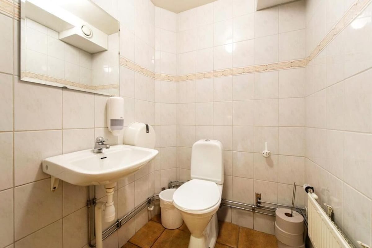 A small, clean bathroom with a white sink, toilet, and mirror.