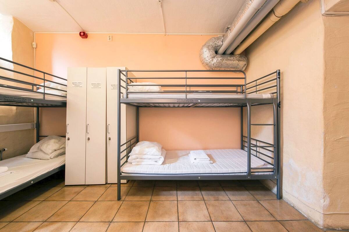 A bunk room with two beds, a wardrobe, and a ventilation duct.