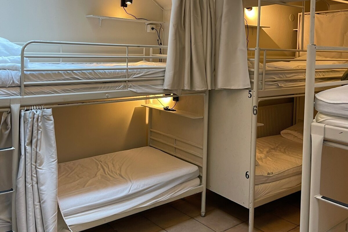 Ein Schlafsaalzimmer mit Etagenbetten, einer Pendelleuchte und einer Heizung.