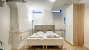 A room with a bed, a radiator, a wooden door, and a plant. - Nomad Cave (Stockholm)
