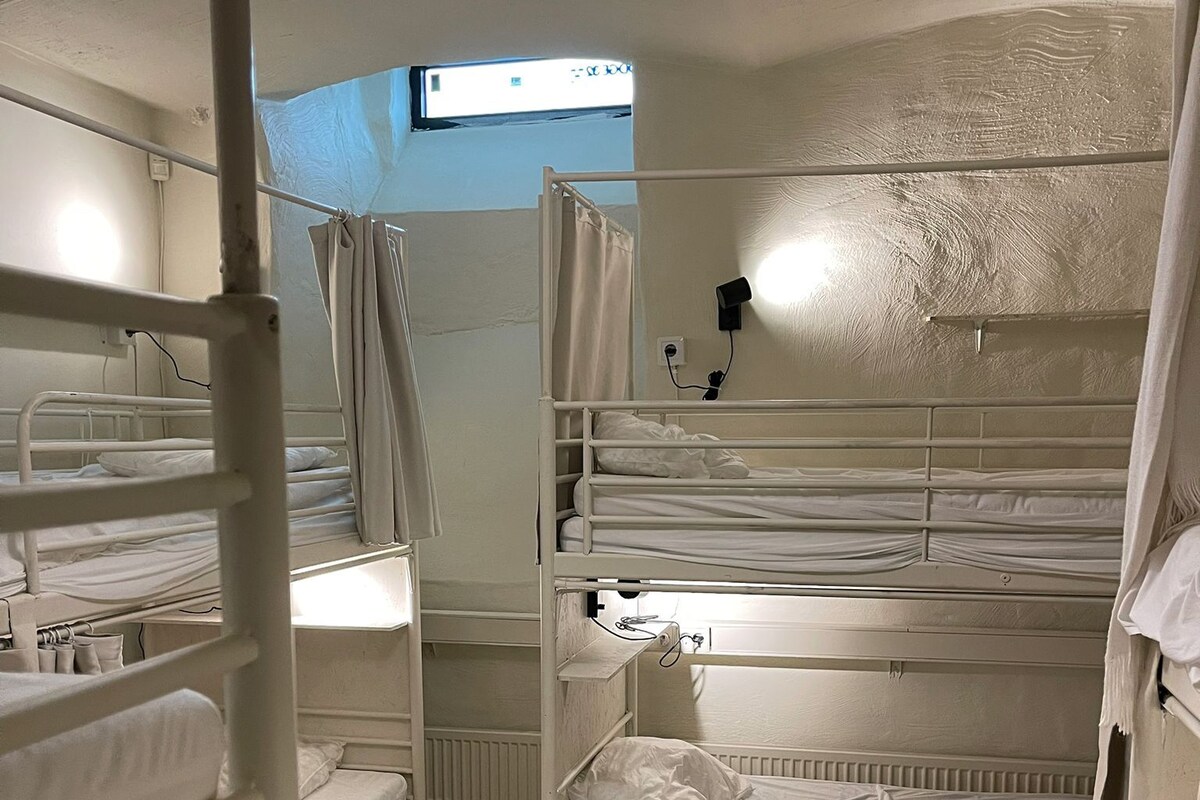 Ein Schlafraum mit Mehrbettzimmer, einem Fenster und einer Deckenleuchte.