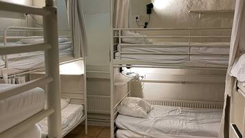 A bunk room with multiple beds, a window, and a ceiling light fixture.