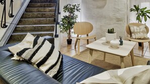 A modern living room with a staircase, a flat-screen TV, and a view of a cityscape. - Nomad Cave (Stockholm)