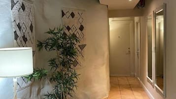 Un pasillo con una planta en maceta, una lámpara y un suelo de baldosas.