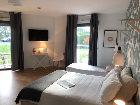 A hotel room with two beds, a desk with a chair, a TV, and a window with curtains. - Hôtel & Events Le Patio Occitan – Toulouse Ouest Cugnaux (Cugnaux)