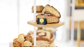 Una exhibición de panes y pasteles sobre un soporte de madera.