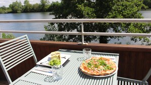 Una mesa de comedor con una pizza y un sándwich, con vistas a un lago.