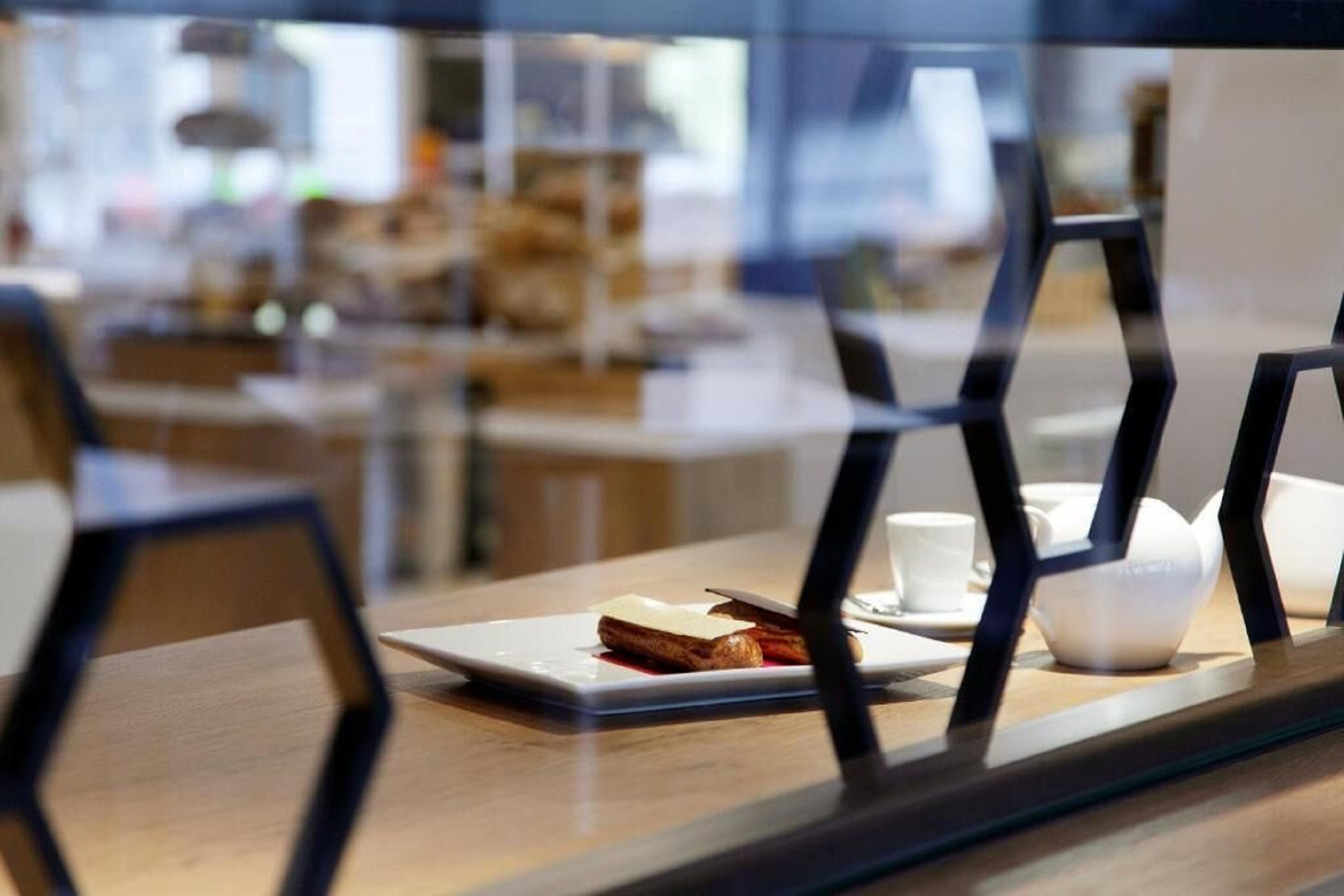 A dining area with a table set for two, featuring a plate with a sandwich and a cup.