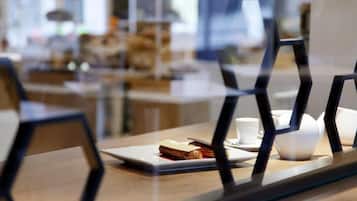 A dining area with a table set for two, featuring a plate with a sandwich and a cup.