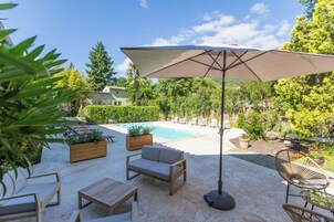 Un patio trasero con piscina, muebles de exterior y plantas en macetas.