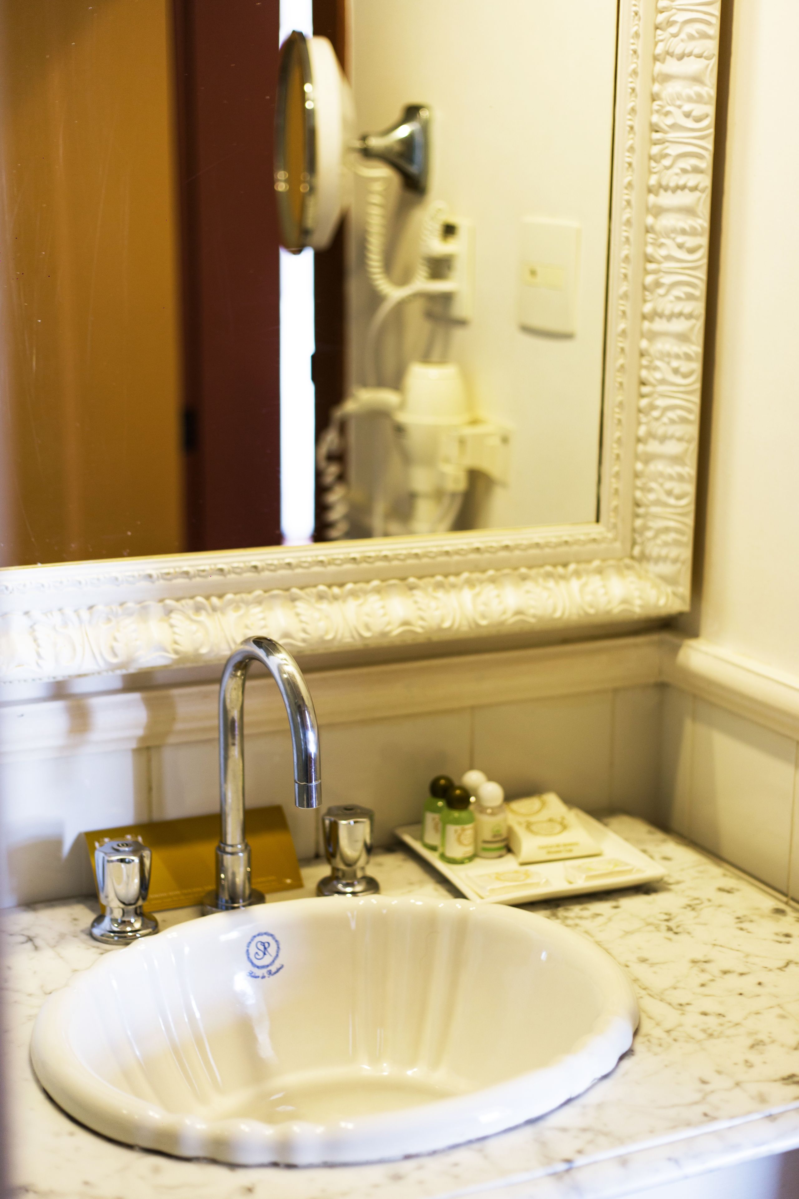 A bathroom with a white sink, a mirror, and a towel rack.