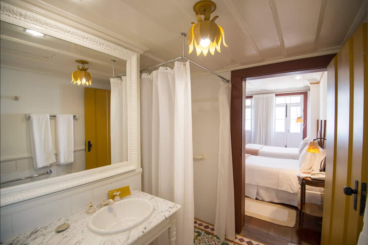 Un baño con un espejo grande, lavamanos blanco y cortina de ducha.