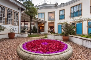 Ein Innenhof mit einem kreisförmigen Blumenbeet, weißen Wänden und blauen Türen.