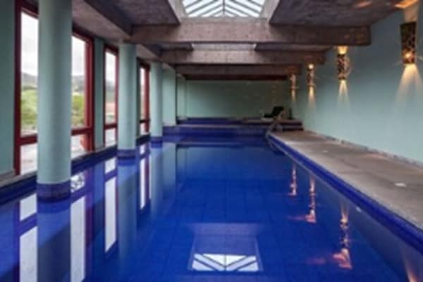 Una piscina techada, una piscina al aire libre, sombrillas