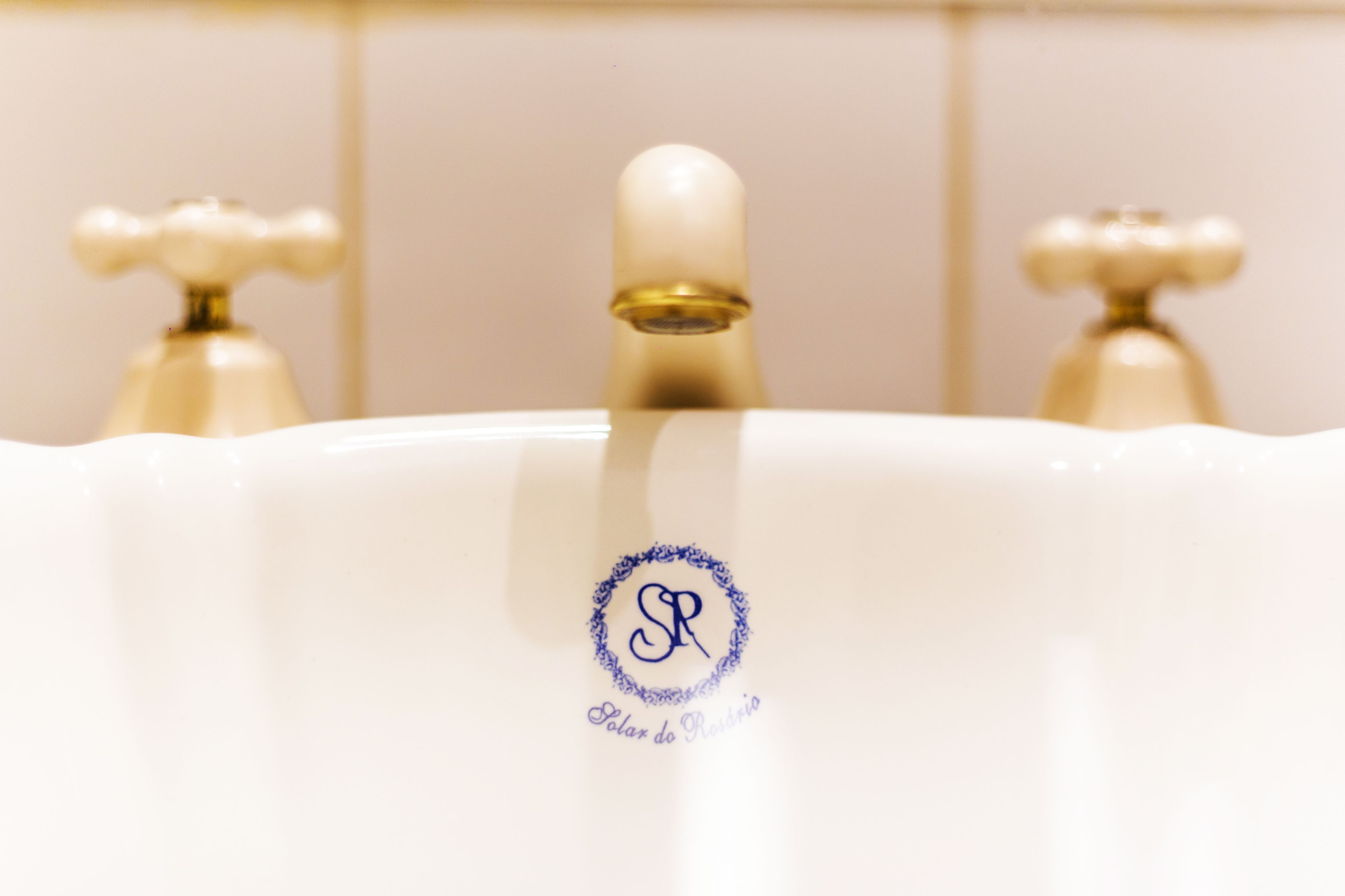 A bathroom sink with a white basin and a gold faucet.