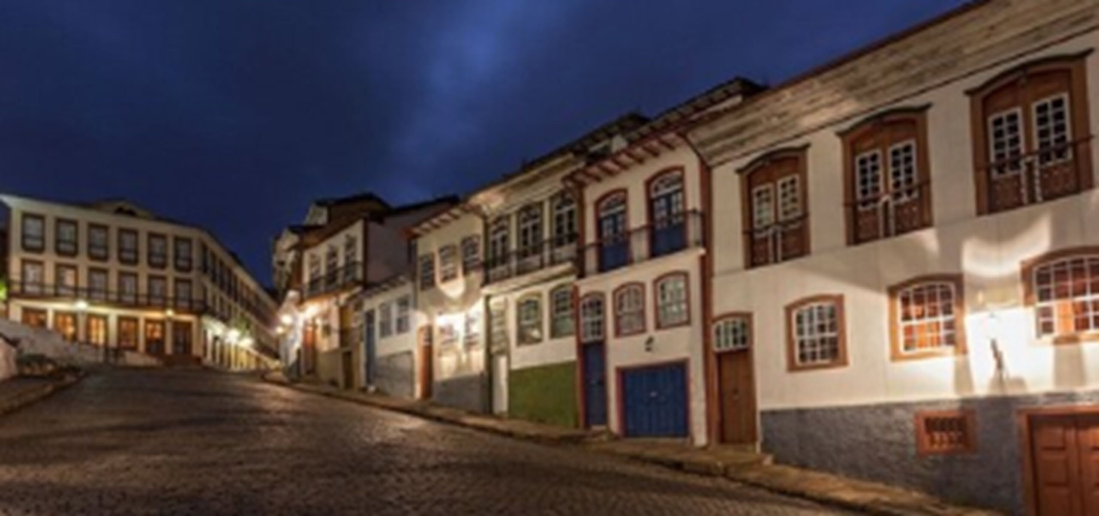 A cobblestone street lined with historic buildings featuring traditional architecture and warm lighting.