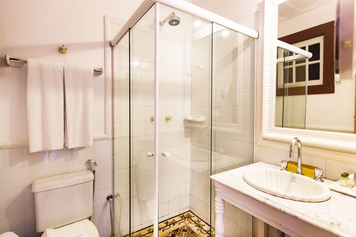 Un baño con ducha de vidrio, inodoro y lavamanos con espejo.