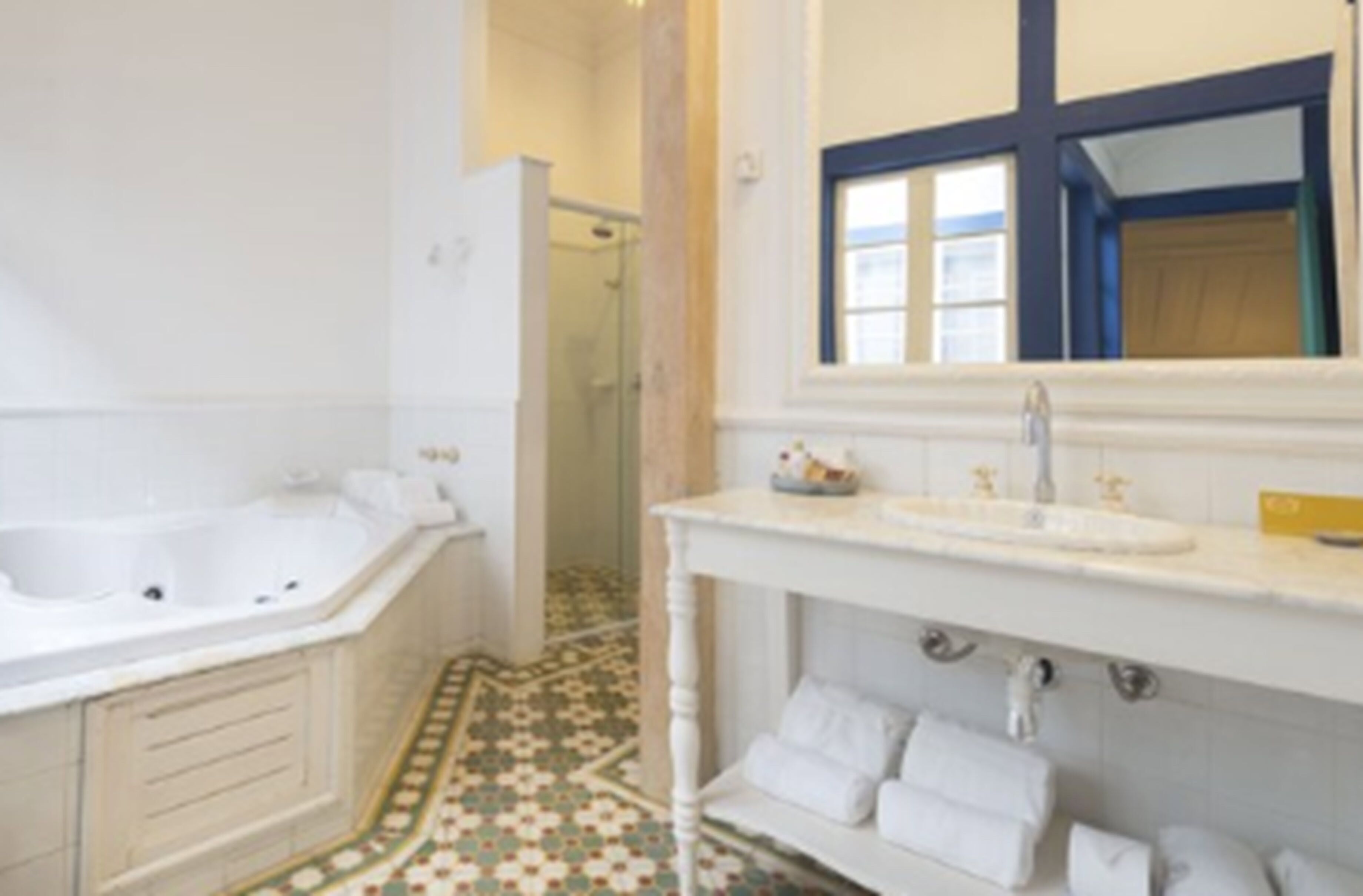 Ein Badezimmer mit einer weißen Badewanne, einem Waschbecken mit Spiegel und einer Duschkabine.