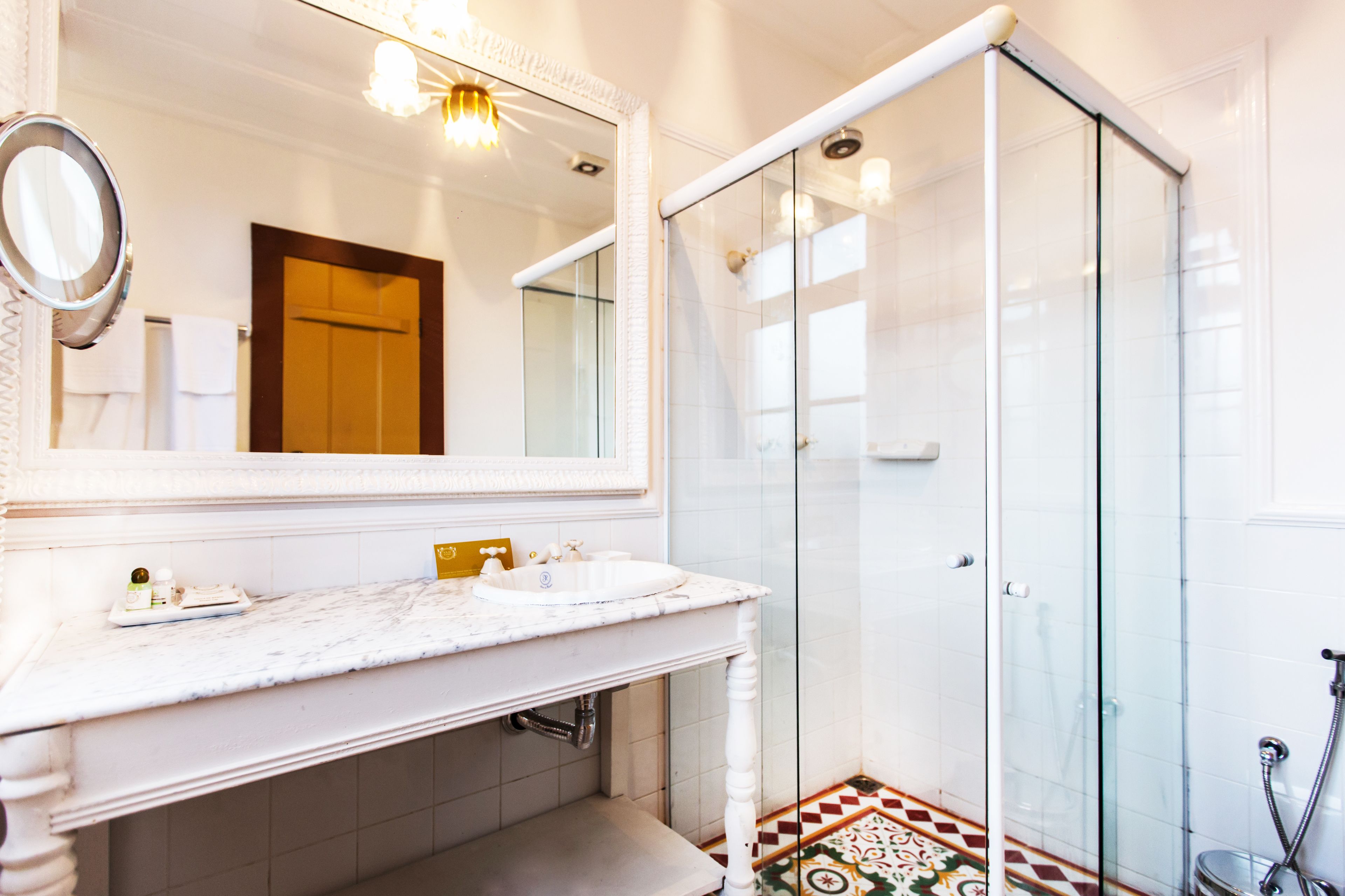 Un baño con lavamanos de mármol, un espejo grande y cabina de ducha con paredes de cristal.