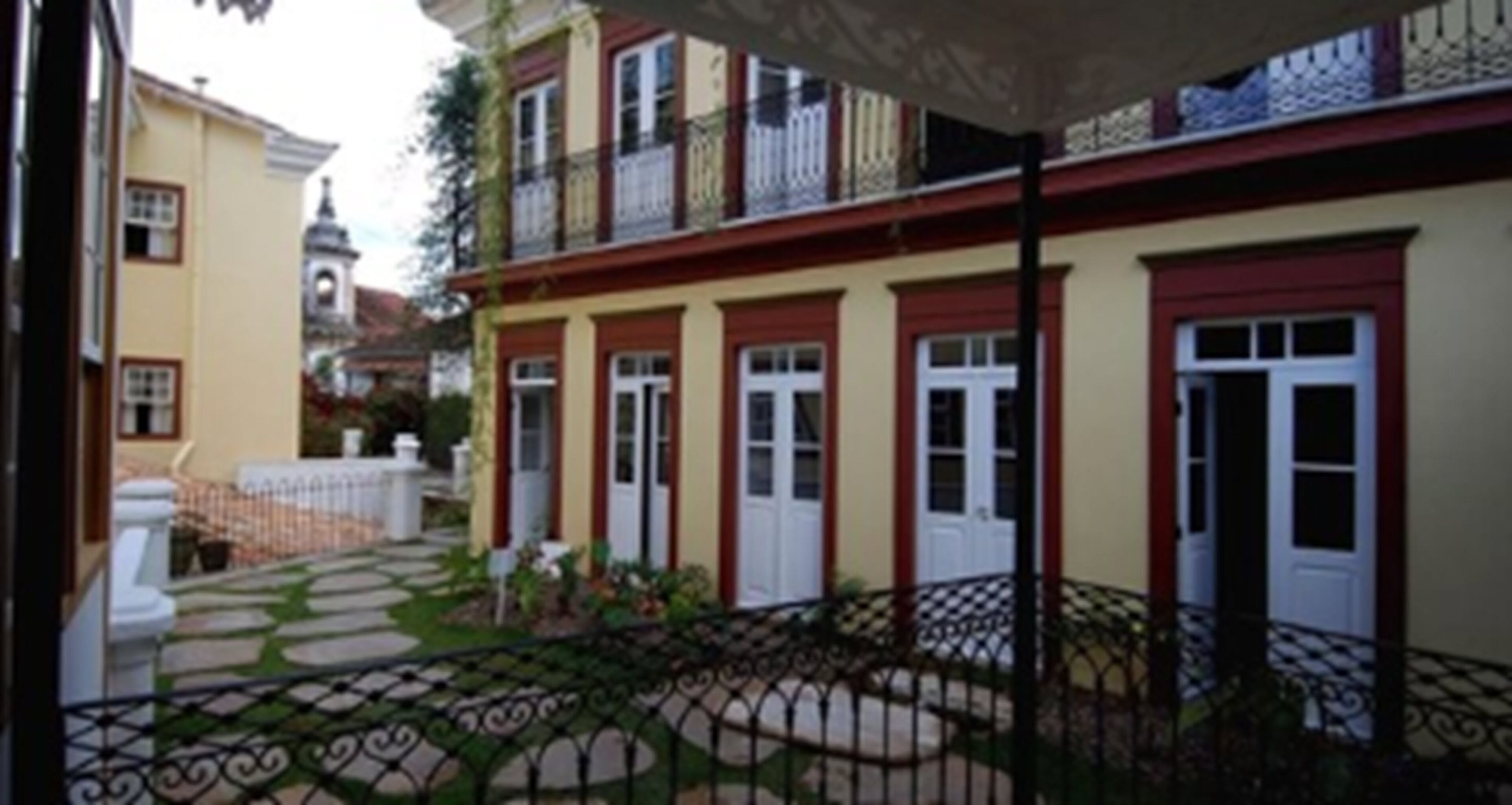 A courtyard with a patterned walkway, a white door, and a balcony with a railing.