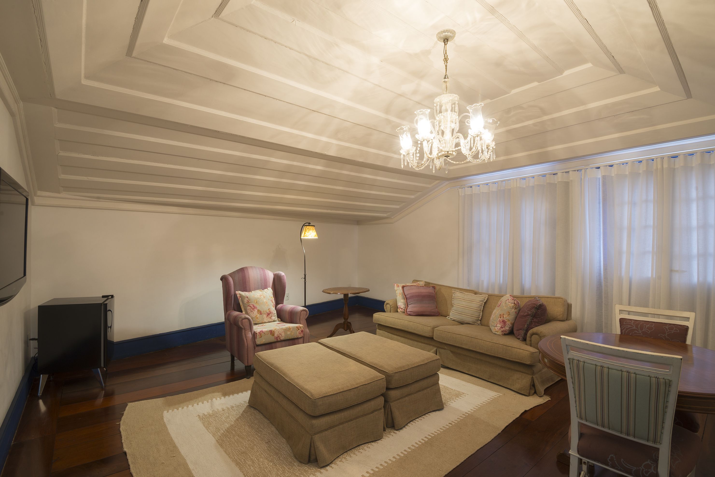 A living room with a sofa, ottoman, armchair, and a chandelier.