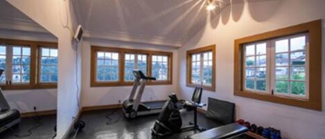 A gym with treadmills, a stationary bike, a rowing machine, and weightlifting equipment.