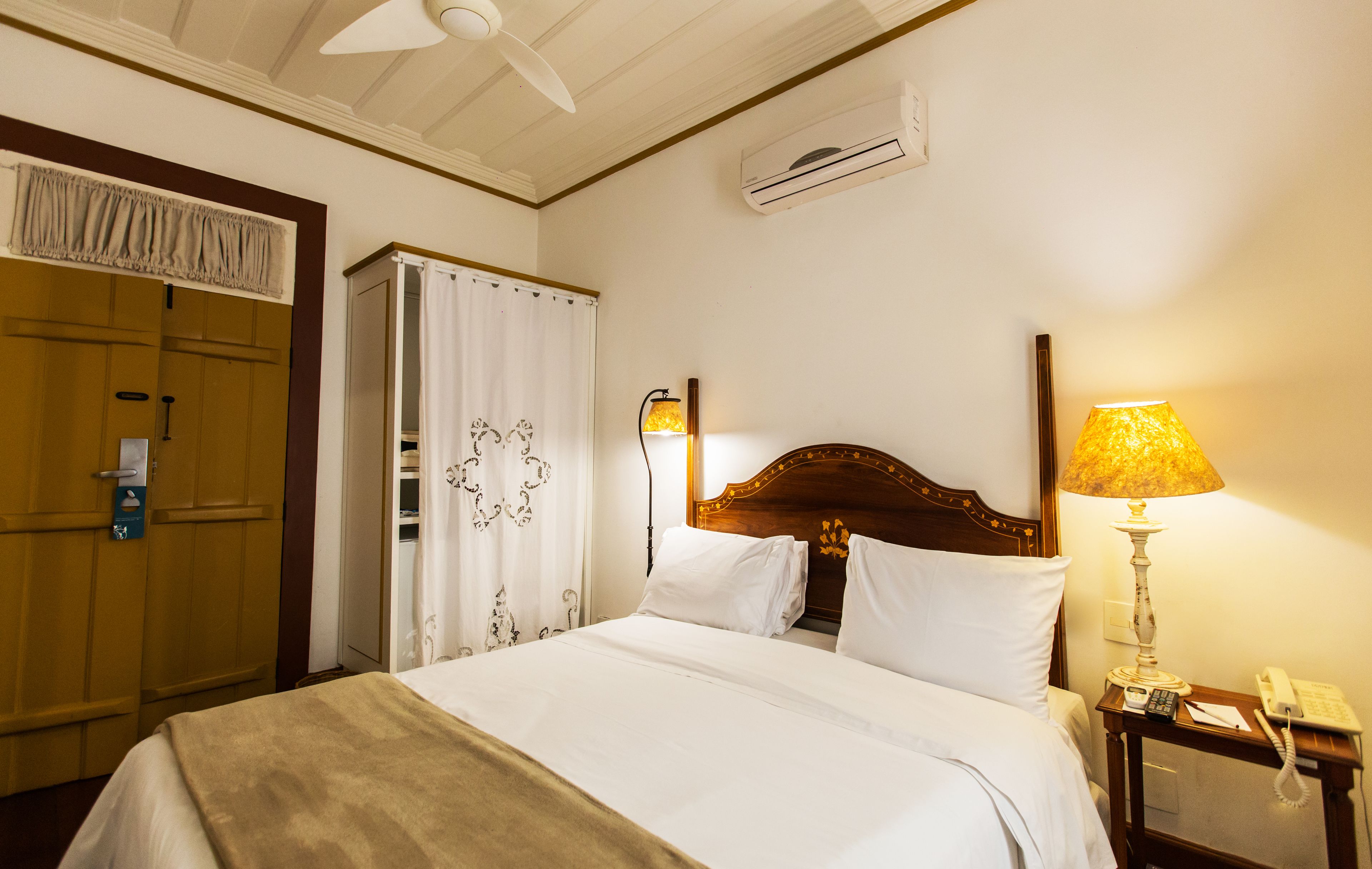 Hotelkamer met een bed, nachtkastje met lamp, kast en airconditioning.